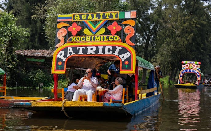 Xochimilco trajinera with tourists enjoying a canal ride in Mexico City.
