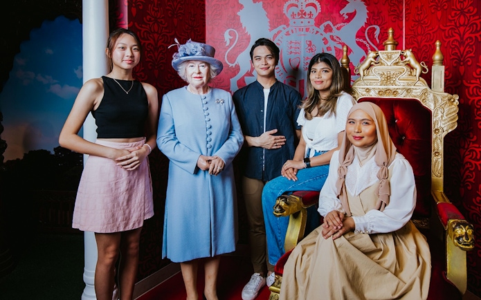 Visitors posing with a wax figure of the queen at Madame Tussauds Singapore.