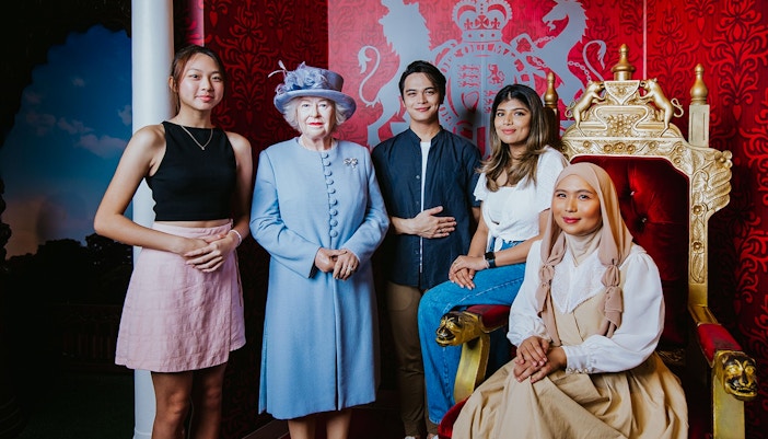 Visitors posing with a wax figure of the queen at Madame Tussauds, Singapore.