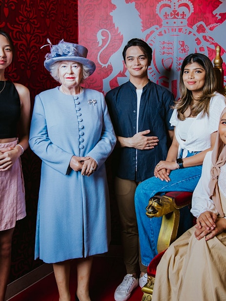 Visitors posing with a wax figure of the queen at Madame Tussauds Singapore.