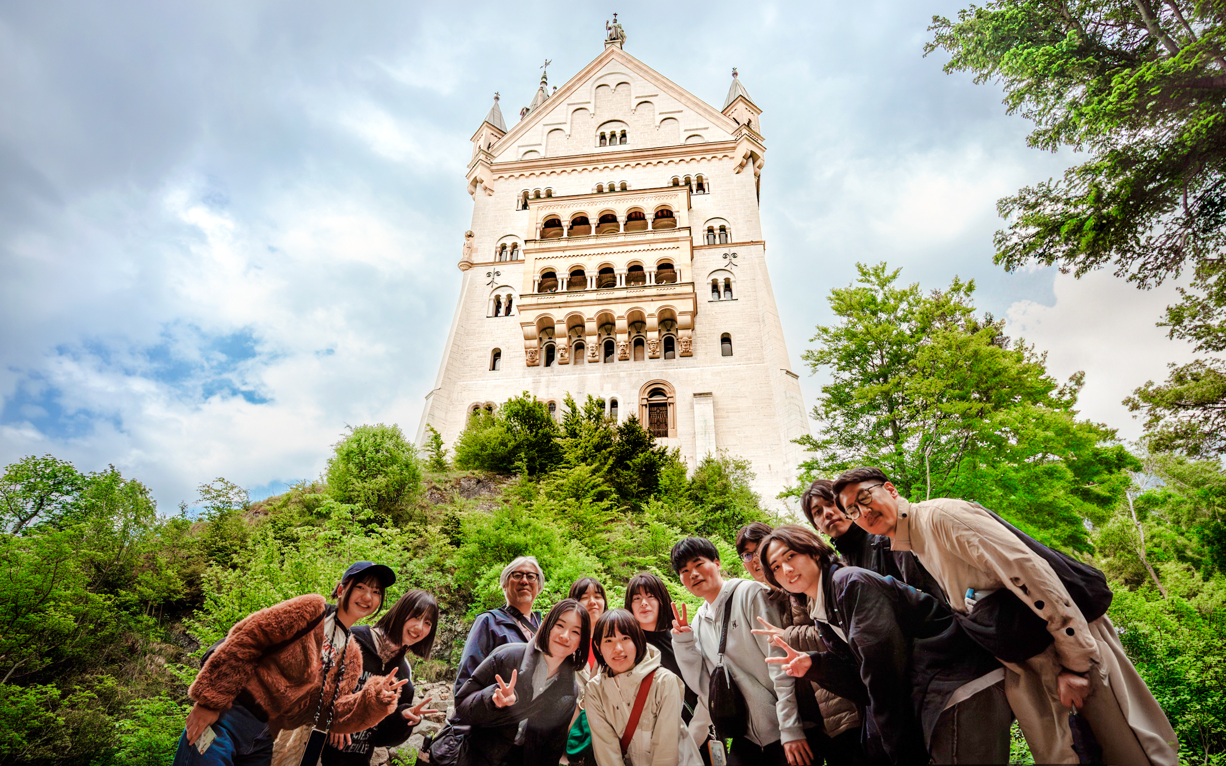 Tourists posing in front of Neuschwanstein Castle, Germany.