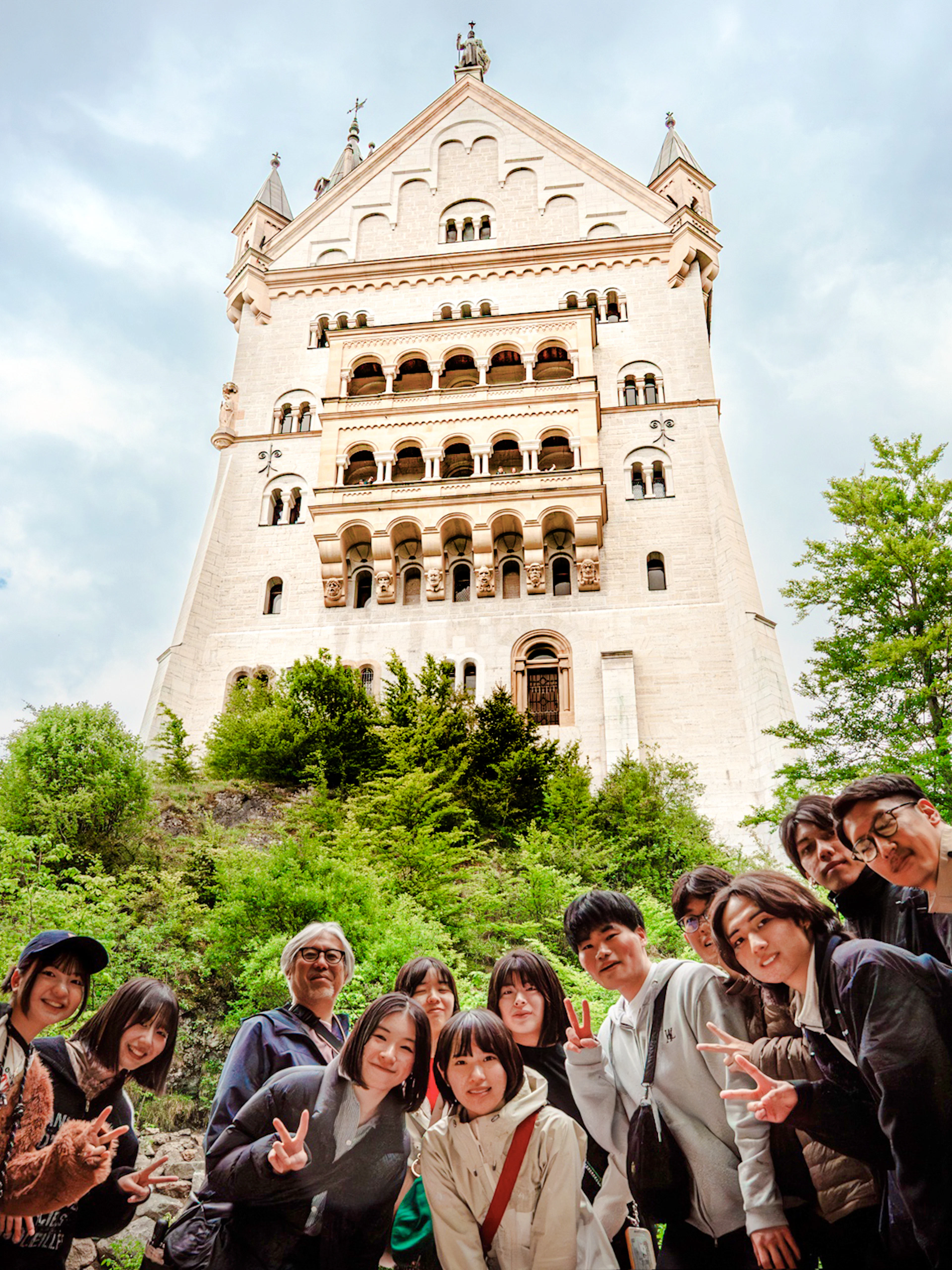 Tourists posing in front of Neuschwanstein Castle, Germany.