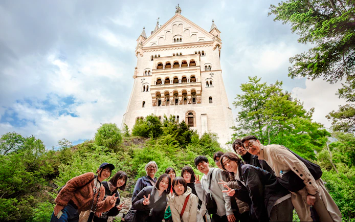 Tourists posing in front of Neuschwanstein Castle, Germany.