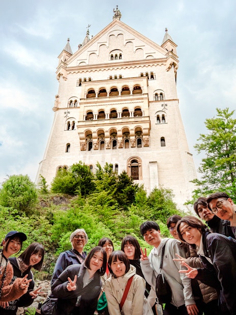 Tourists posing in front of Neuschwanstein Castle, Germany.