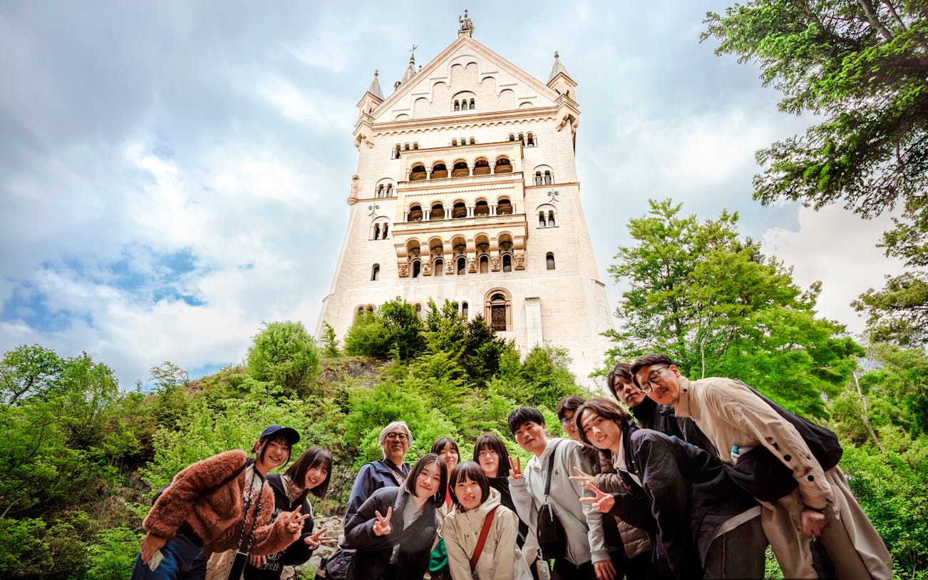 Tourists posing in front of Neuschwanstein Castle, Germany.