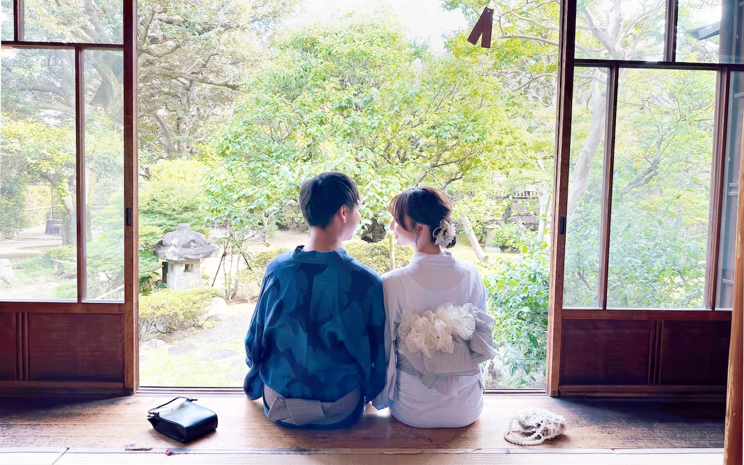 Couple in traditional Japanese attire sitting in a serene Japanese garden.