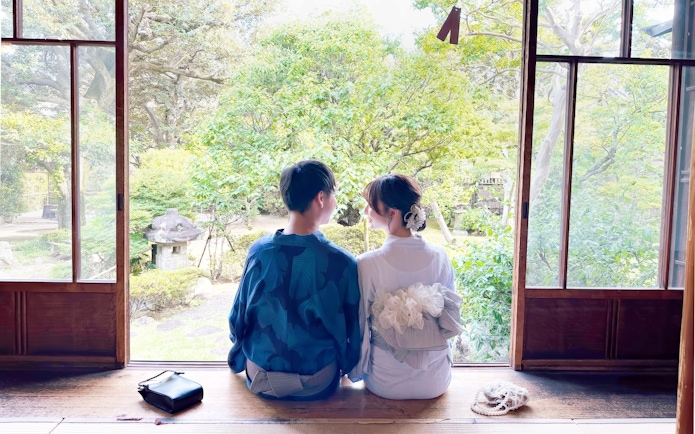 Couple in traditional Japanese attire sitting in a serene Japanese garden.