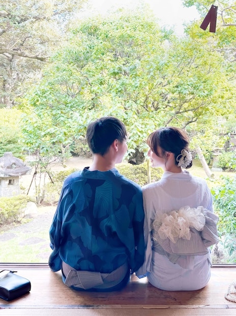 Couple in traditional Japanese attire sitting in a serene Japanese garden.