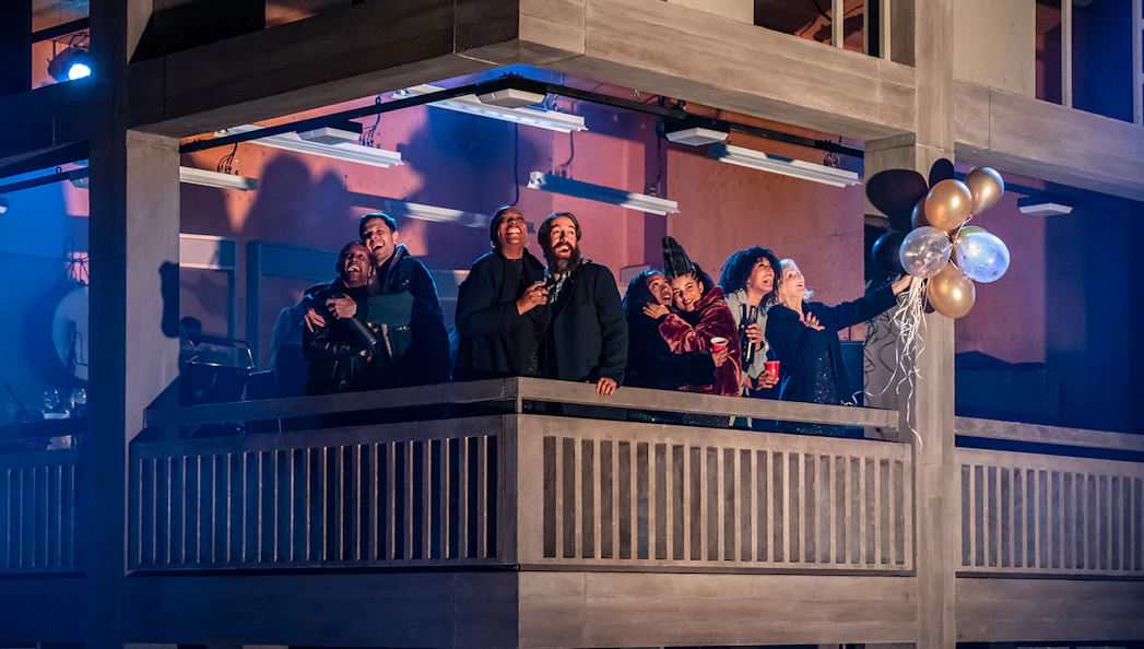 Group of people celebrating on a balcony during Standing at the Sky's Edge Westend performance.