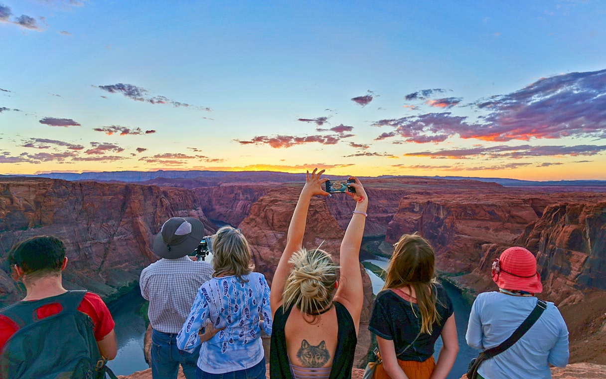 Tourists at Horseshoe Bend, Las Vegas, capturing sunset views over the canyon.
