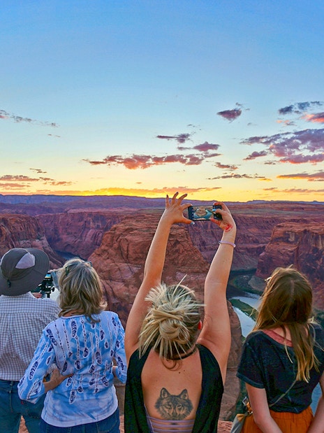 Tourists at Horseshoe Bend, Las Vegas, capturing sunset views over the canyon.