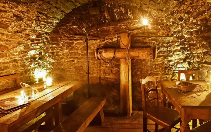 Medieval dining room in Prague with wooden tables and stone walls.
