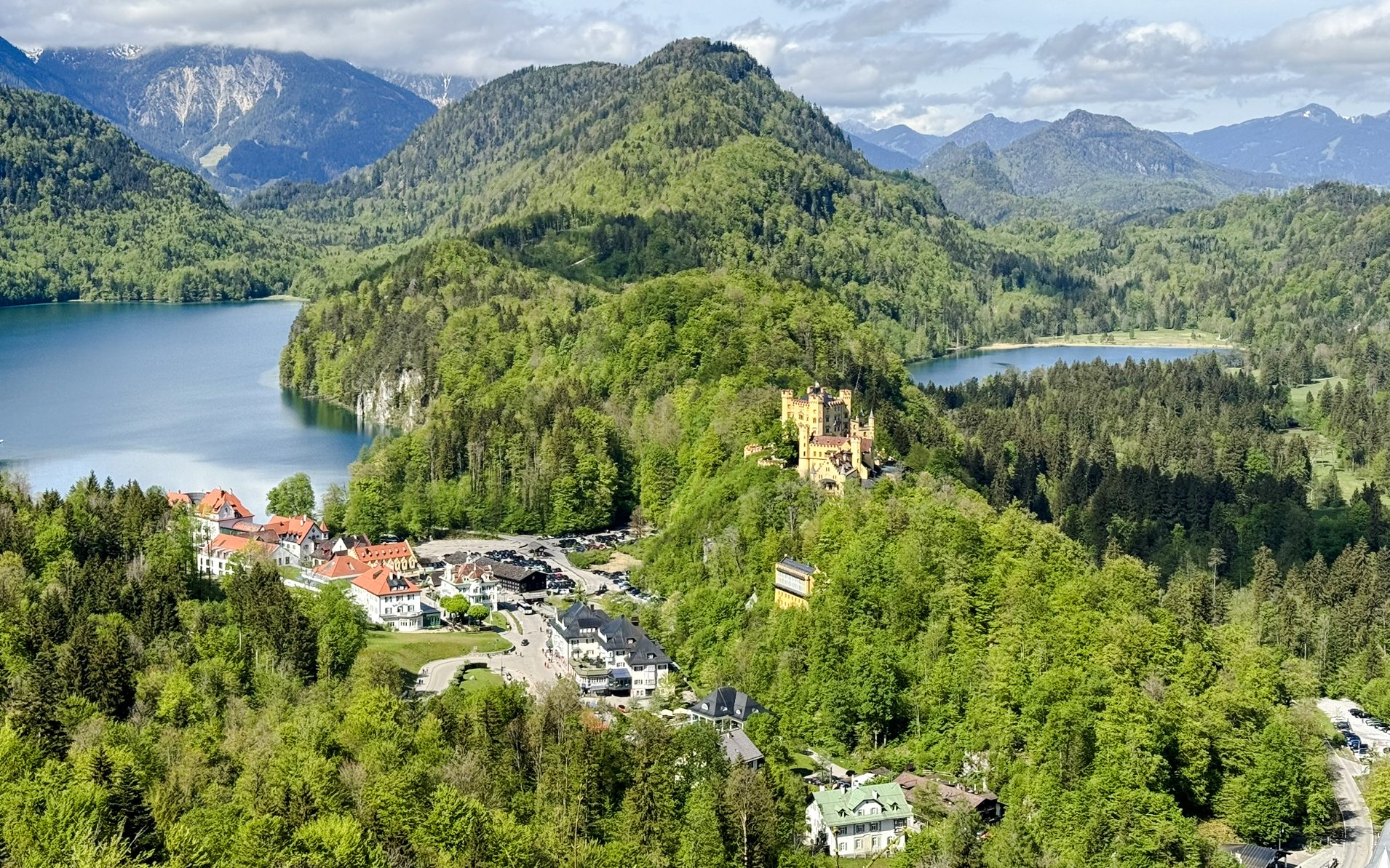 Hohenschwangau Castle surrounded by lush greenery and lakes in the Alps, Germany.