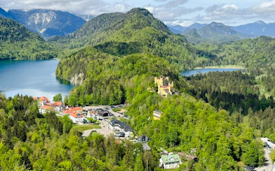 Hohenschwangau Castle surrounded by lush greenery and lakes in the Alps, Germany.