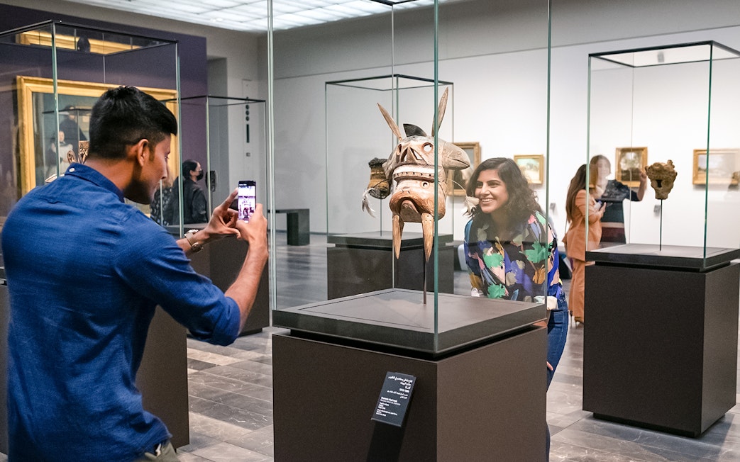 Visitors at Louvre Abu Dhabi viewing an artifact, part of a combo offer with National Aquarium tickets.