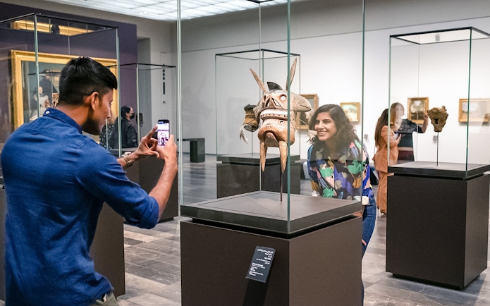 Visitors at Louvre Abu Dhabi viewing an artifact, part of a combo offer with National Aquarium tickets.