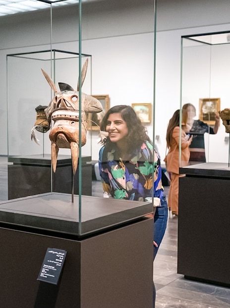 Visitors at Louvre Abu Dhabi viewing an artifact, part of a combo offer with National Aquarium tickets.