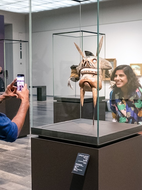 Visitors at Louvre Abu Dhabi viewing an artifact, part of a combo offer with National Aquarium tickets.
