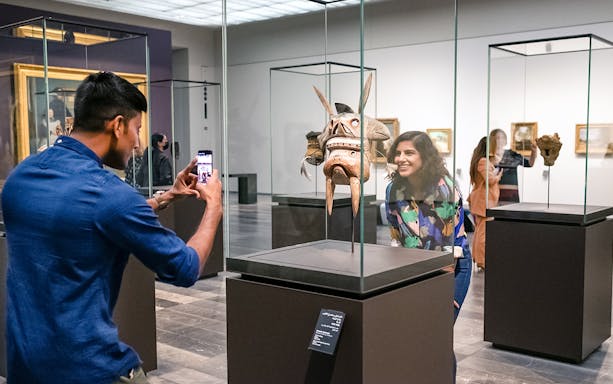 Visitors at Louvre Abu Dhabi viewing an artifact, part of a combo offer with National Aquarium tickets.