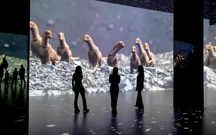 Guests viewing dinosaur projections at Phoenix des Lumières Dortmund exhibition.