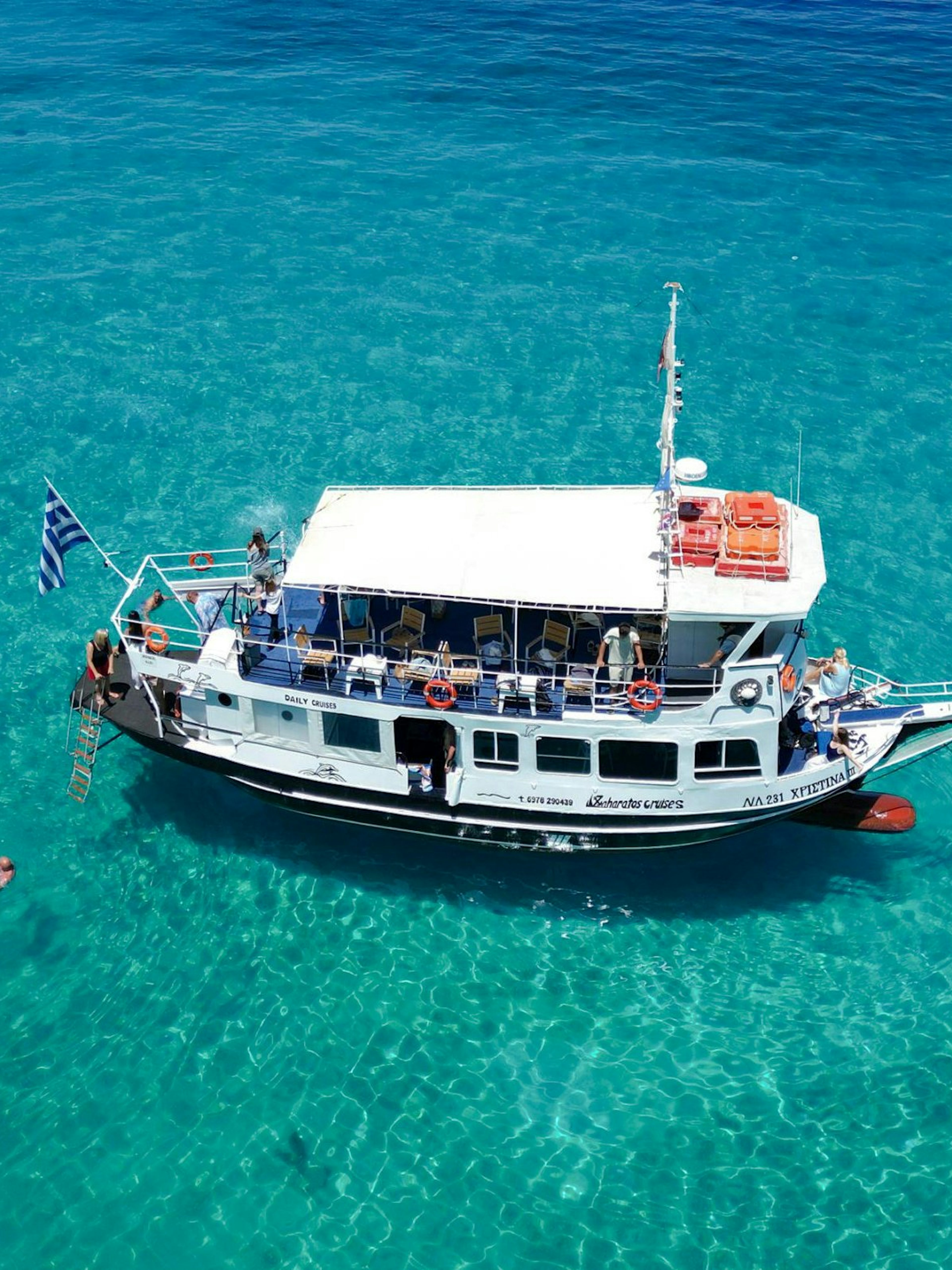 Cruise boat on clear blue waters with swimmers, Ithaca Cruise, Kefalonia, Greece.
