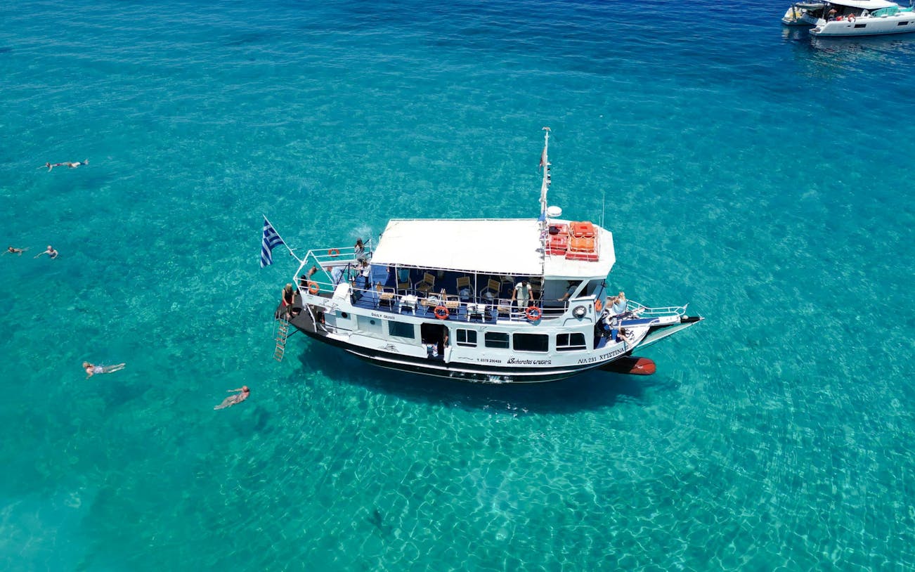 Cruise boat on clear blue waters with swimmers, Ithaca Cruise, Kefalonia, Greece.