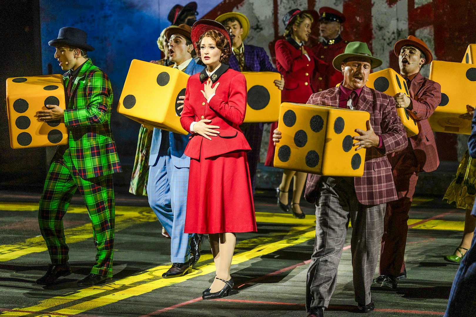 Performers in colorful costumes holding large dice during "Guys & Dolls" on Sydney Harbour.