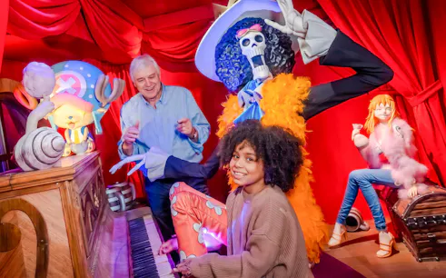 Child playing piano with wax figures at Grévin Paris Wax Museum.