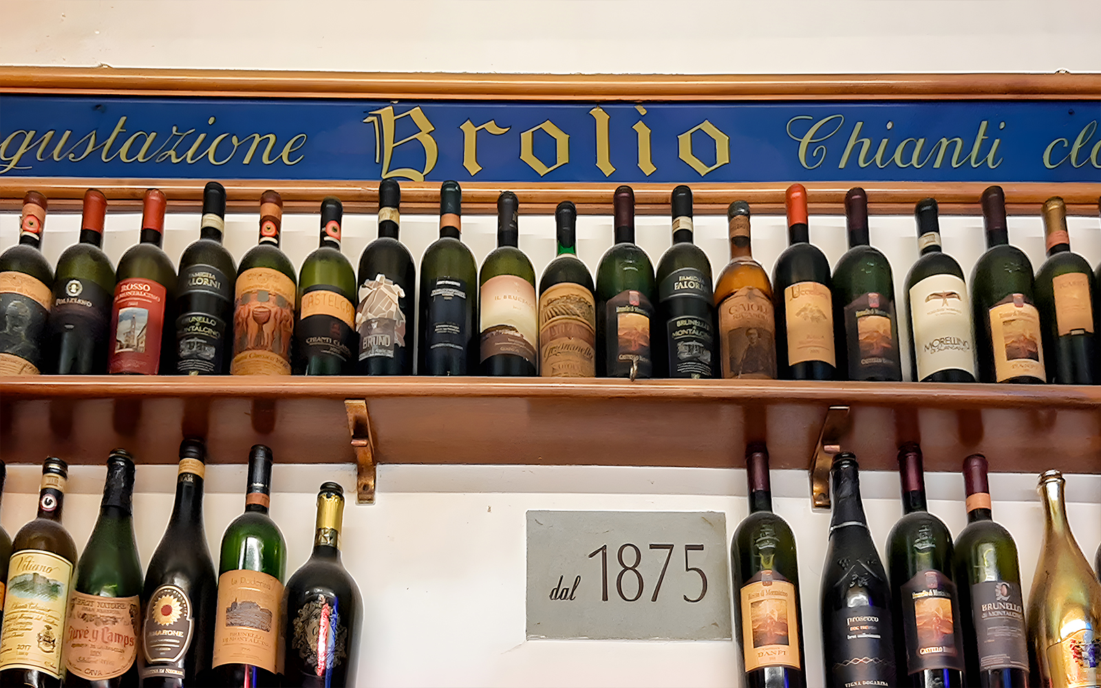 Wine bottles displayed on a shelf at All’Antico Vinaio, Florence, with a sign reading "dal 1875.