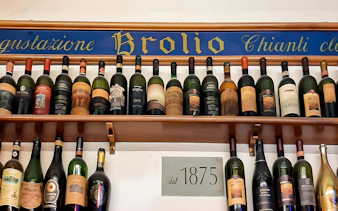 Wine bottles displayed on a shelf at All’Antico Vinaio, Florence, with a sign reading "dal 1875.