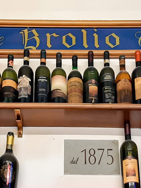 Wine bottles displayed on a shelf at All’Antico Vinaio, Florence, with a sign reading "dal 1875.