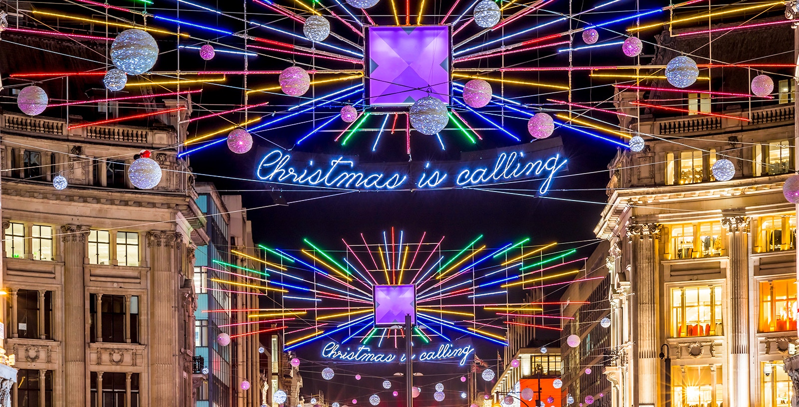 London Christmas lights display with "Christmas is calling" sign on Oxford Street.