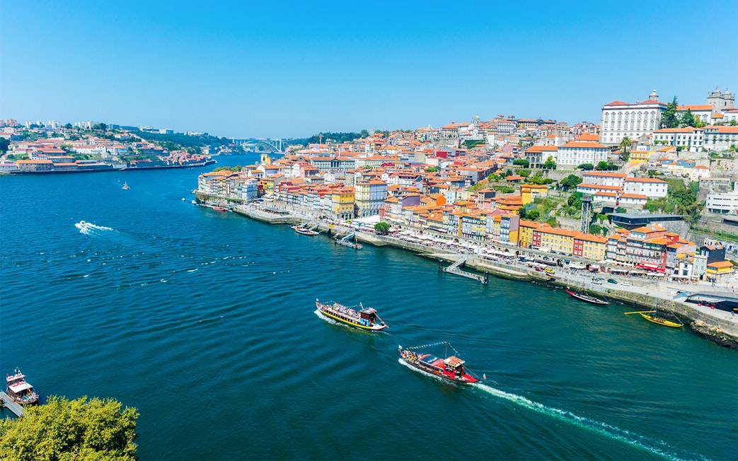 Boats on the Douro River with Porto's colorful riverside buildings in view.