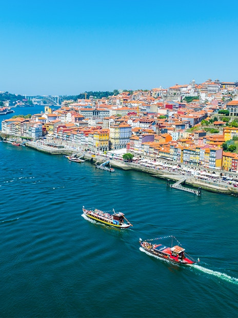 Boats on the Douro River with Porto's colorful riverside buildings in view.