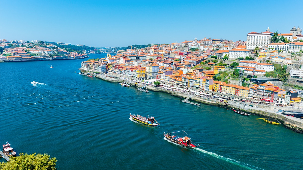 Boats on the Douro River with Porto's colorful riverside buildings in view.