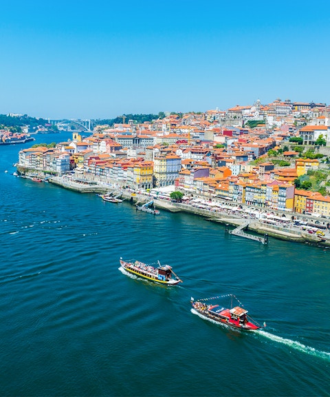 Boats on the Douro River with Porto's colorful riverside buildings in view.