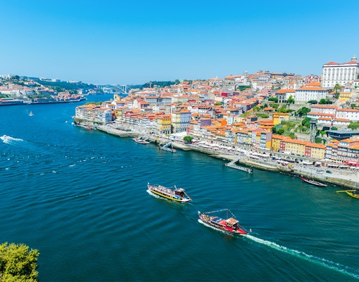 Boats on the Douro River with Porto's colorful riverside buildings in view.