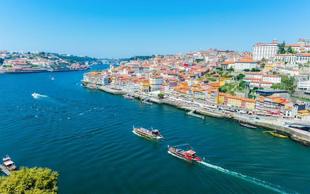 Boats on the Douro River with Porto's colorful riverside buildings in view.