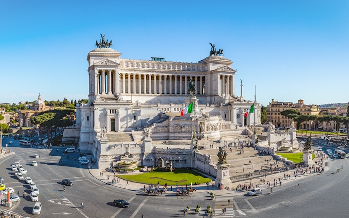 Altare della Patria in Rome with Italian flags and surrounding cityscape.