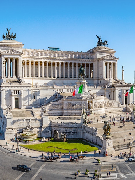 Altare della Patria in Rome with Italian flags and surrounding cityscape.