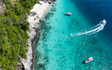 Aerial view of boats near Nemo Island's turquoise waters and rocky shoreline.