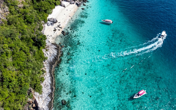 Aerial view of boats near Nemo Island's turquoise waters and rocky shoreline.