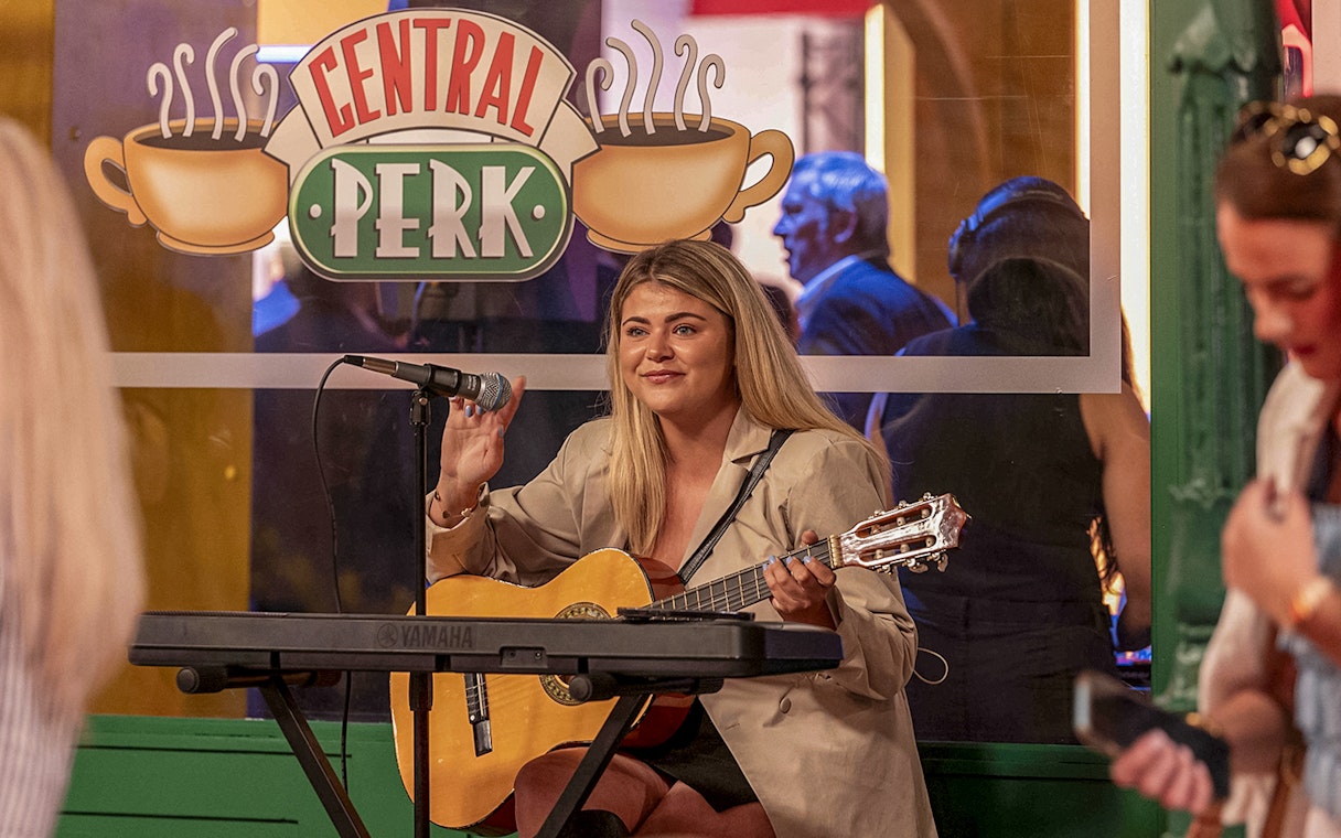 Musician playing guitar at Central Perk during the FRIENDS VIP Experience.