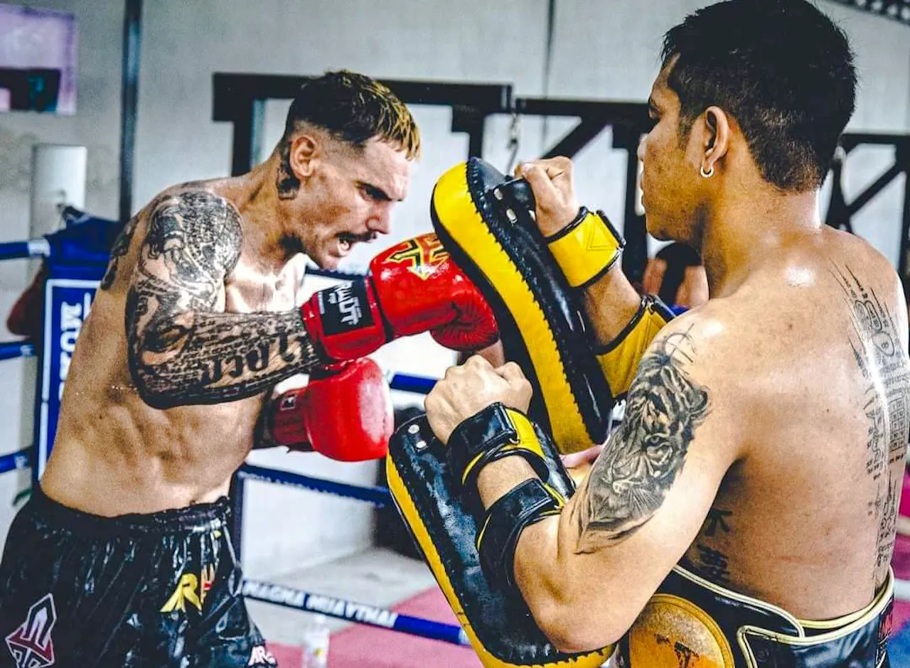 Muay Thai beginner practicing punches with trainer in Pattaya gym.