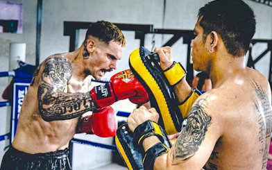 Muay Thai beginner practicing punches with trainer in Pattaya gym.