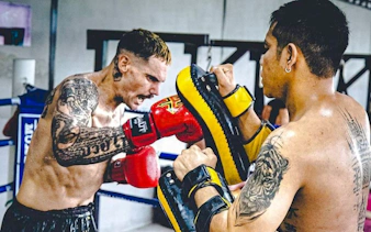 Muay Thai beginner practicing punches with trainer in Pattaya gym.