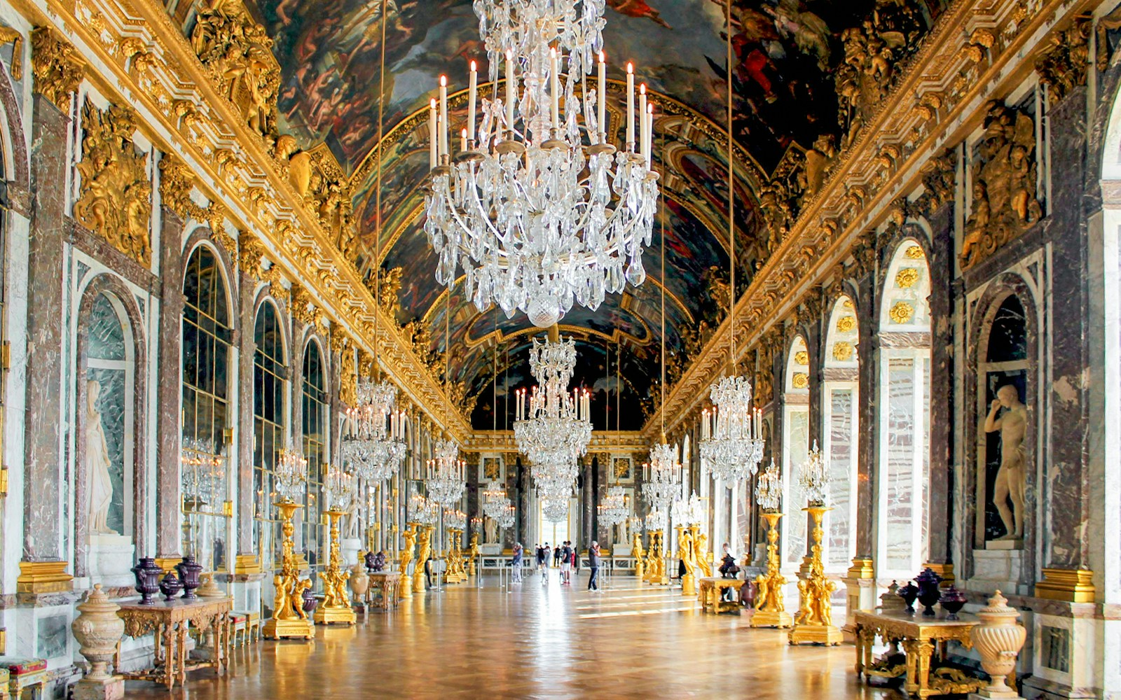 Hall of Mirrors, Versailles Palace, France, showcasing ornate chandeliers and reflective mirrors.