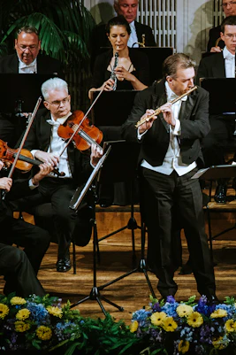 Vienna Hofburg Orchestra performing with musicians playing violins and flutes on stage.