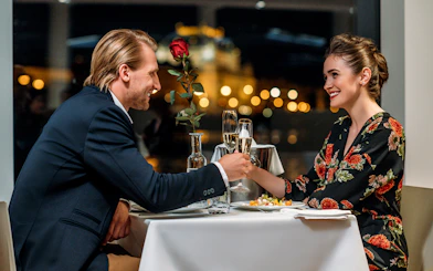 Couple enjoying a romantic dinner cruise in Prague with city lights in the background.