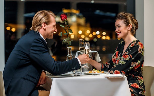 Couple enjoying a romantic dinner cruise in Prague with city lights in the background.